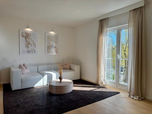 Heller Wohnraum mit weißem Sofa, Beistelltisch und großen Fenstern. Moderne Dekoration.