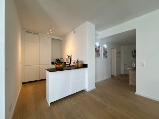 Helle, moderne Küche mit einer weißen Theke und einem angrenzenden Flur.
