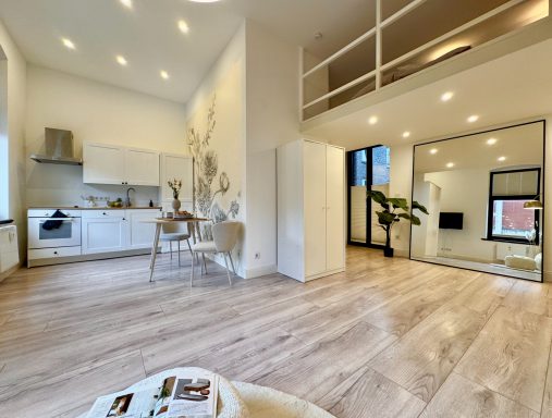 Helles, modernes Apartment mit offener Küche und Balkon, hellen Wänden und Holzfußboden.