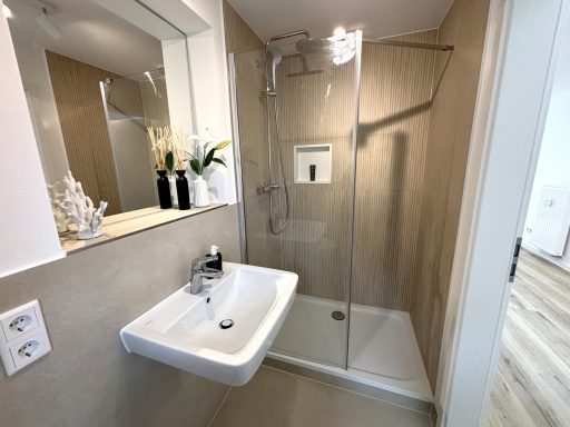 Kleines, modernes Badezimmer mit Dusche, Waschbecken und neutralen Farbtönen.