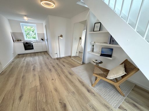 Helles, modernes Zimmer mit Holzfußboden, Schreibtisch und gemütlichem Sessel.