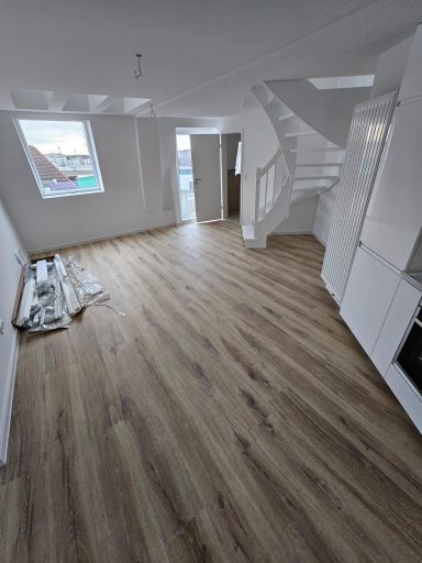 Helle, leere Wohnräume mit neuem Holzboden und einer Wendeltreppe.