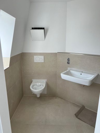 Moderne Toilette mit Waschbecken, hellen Wänden und Bodenfliesen.