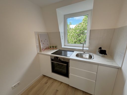 Helle, moderne Küche mit Fenster, Spüle und Herd in neutralem Design.