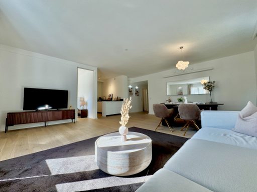 Helles Wohnzimmer mit Sofa, TV, Esstisch und moderner Dekoration.
