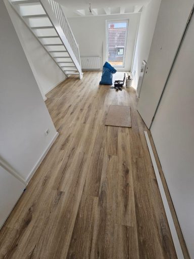 Helle, moderne Innenansicht mit Holzfußboden und Treppe in einem minimalistischen Raum.