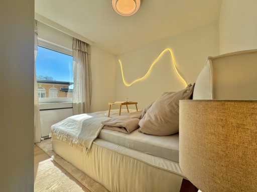 Helles, modernes Schlafzimmer mit einem Bett, Kissen und sanfter Wandbeleuchtung.