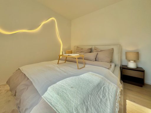 Helles Schlafzimmer mit einem Bett, einer Tischlampe und einem Serviertablett auf dem Bett.