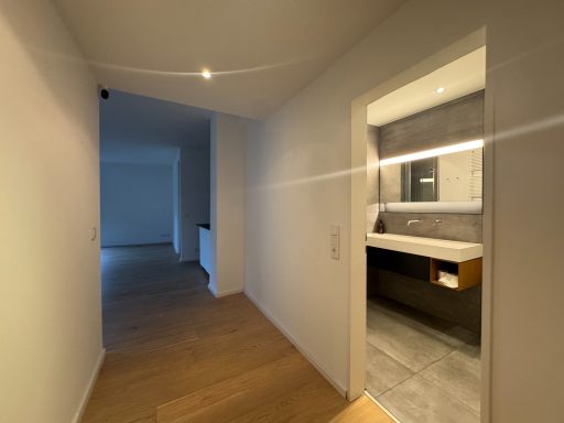 Heller Flur mit Zugang zu einem modernen Badezimmer und einem weiteren Raum.